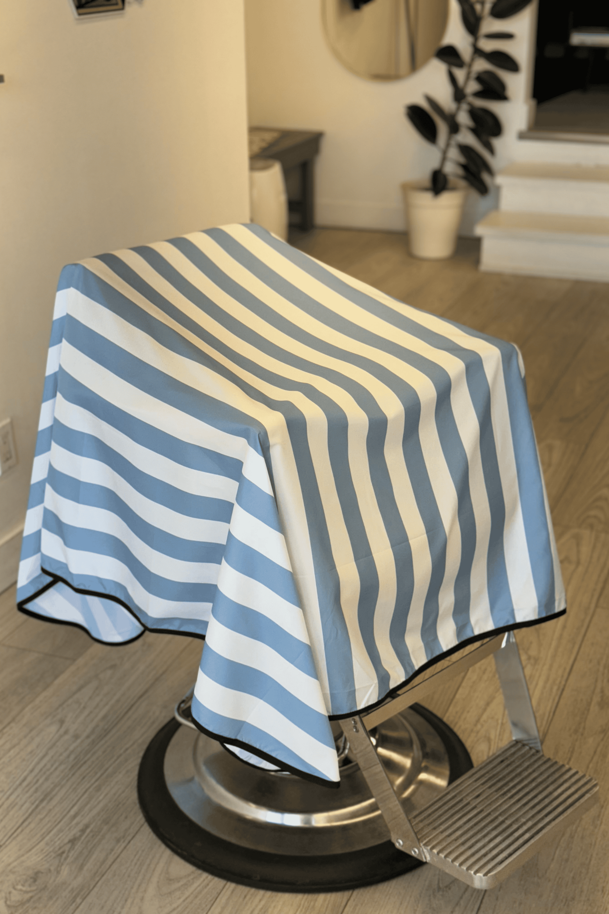 blue and white striped barber cape on barber chair