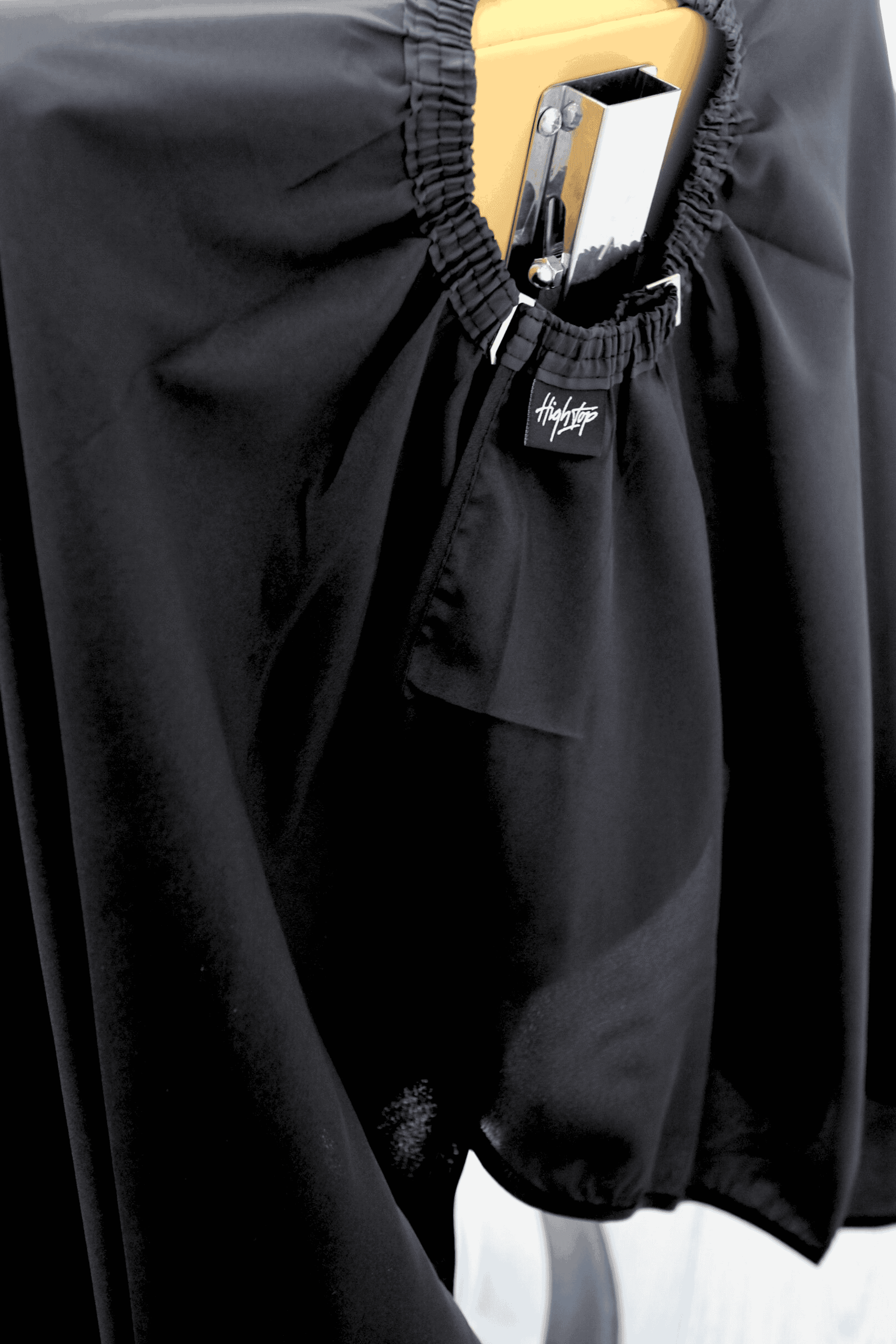 close up of black barber cape neck that is a hook closure and elastic neck