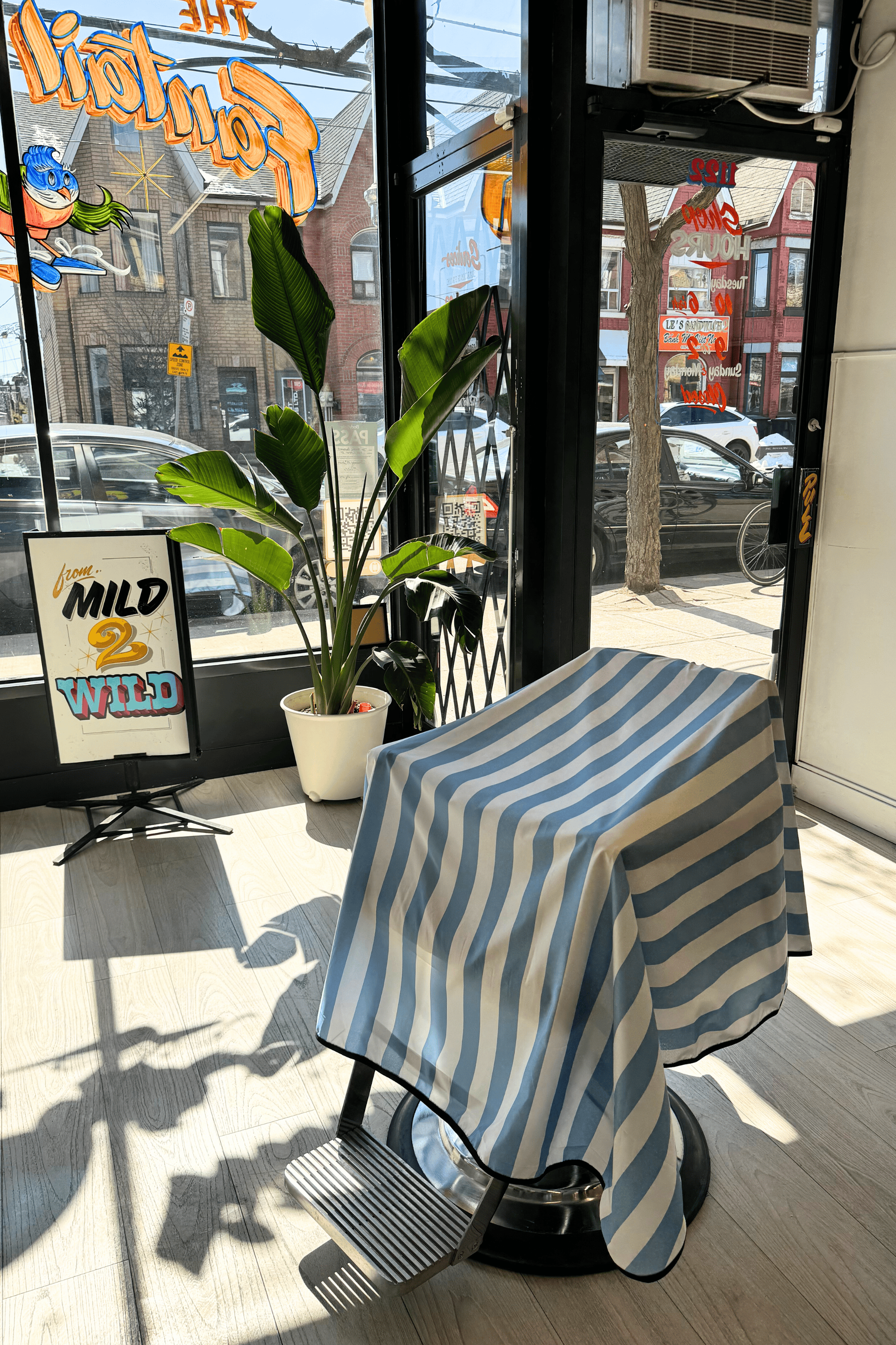 barber chair with blue and white striped cape in window of barbershop