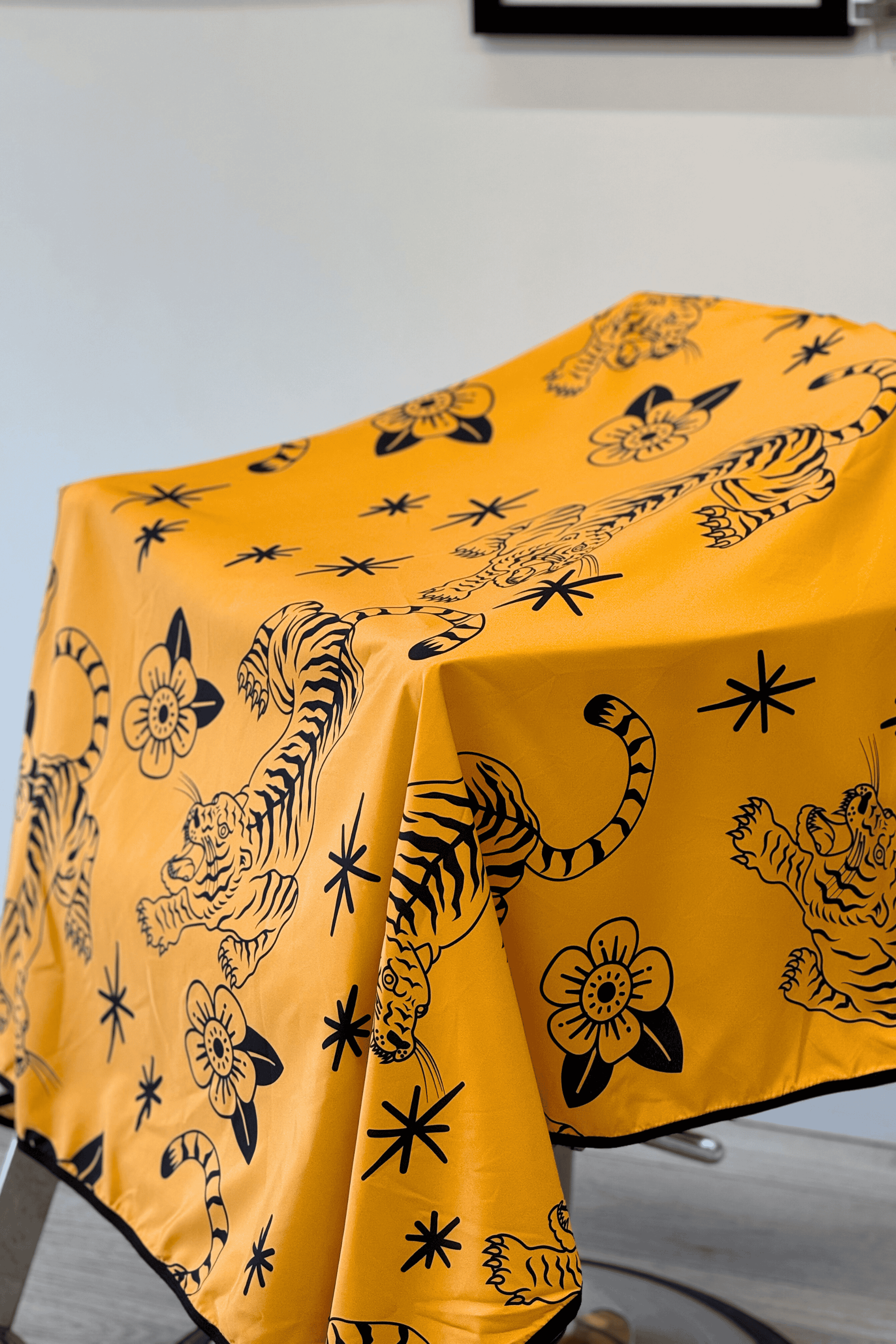 close up of crawling tigers and flowers on yellow tora barber cape