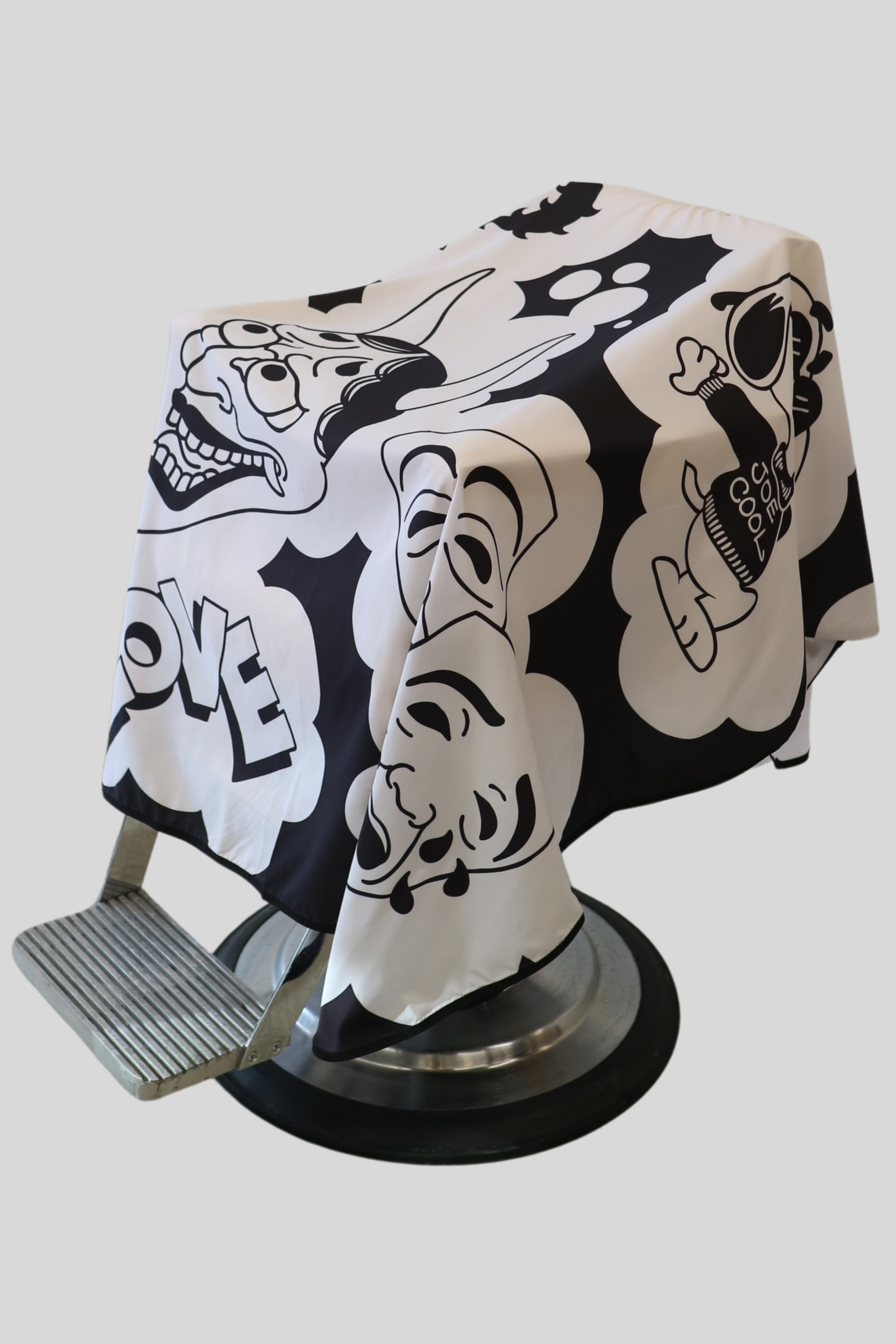 black and white cutting cape with cartoon images. draped over barber chair