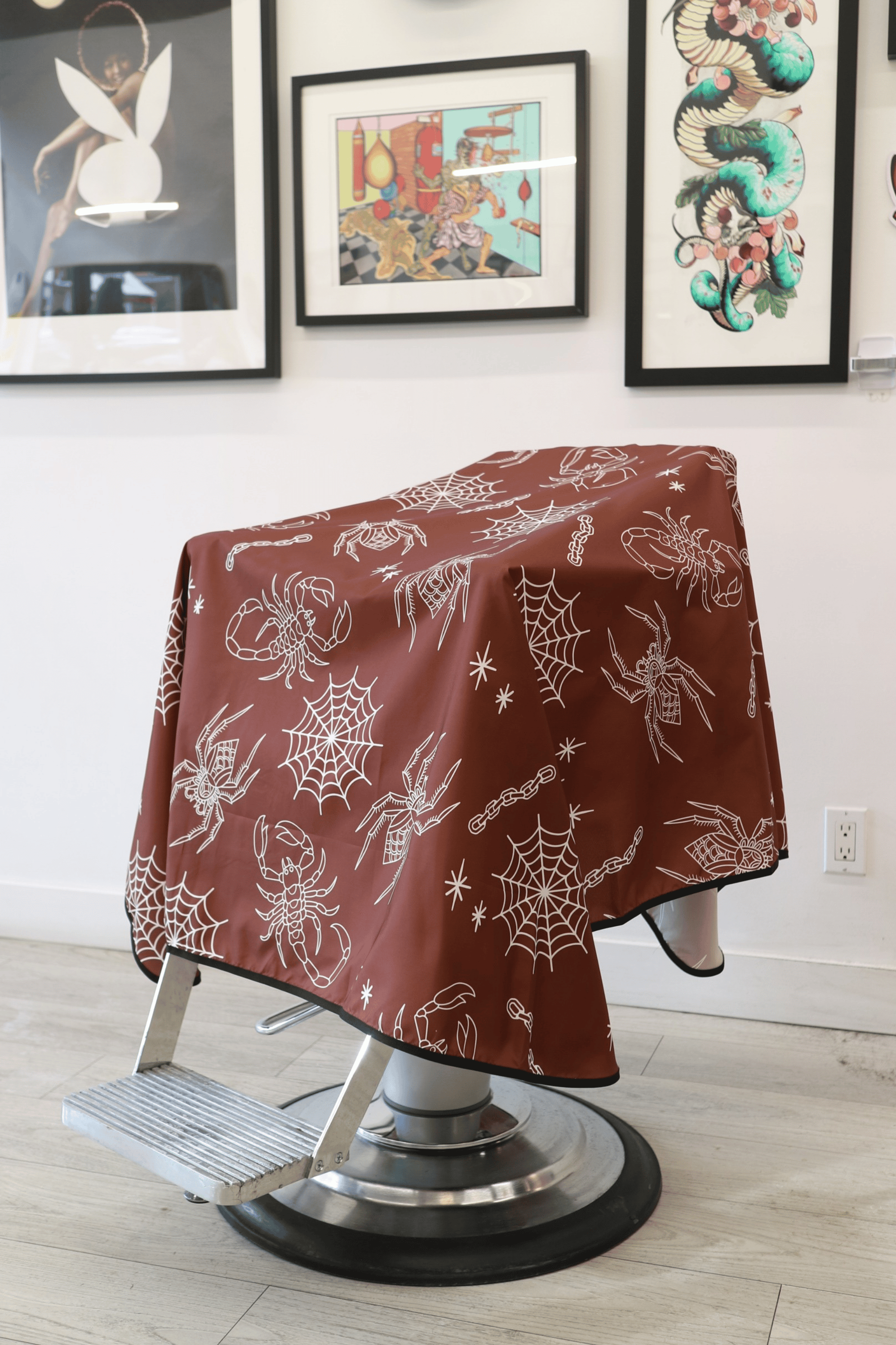 water resistant barber cap draped on barber chair. cape is tattoo style pattern