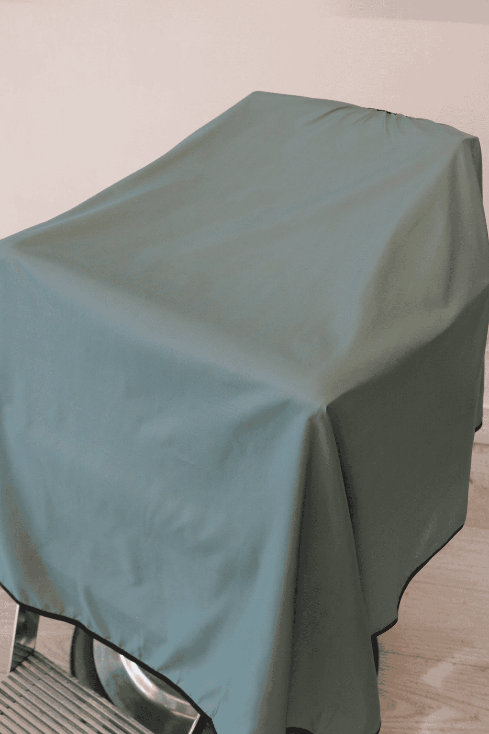 close up shot of the sage solid colored barber cape draped on barber chair