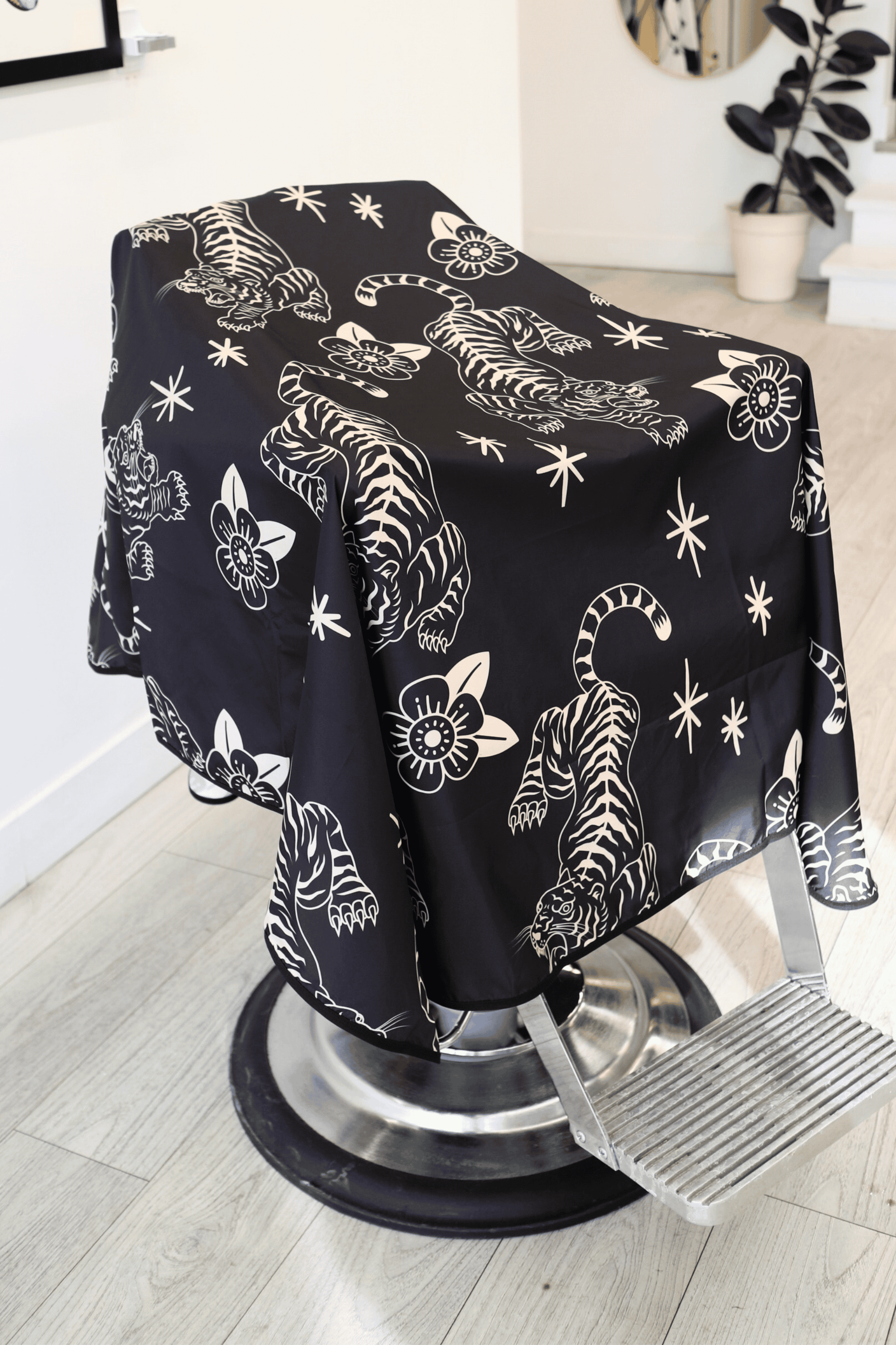 black and cream Tora barber cape showcasing the tattoo style pattern with crawling tiger and flowers