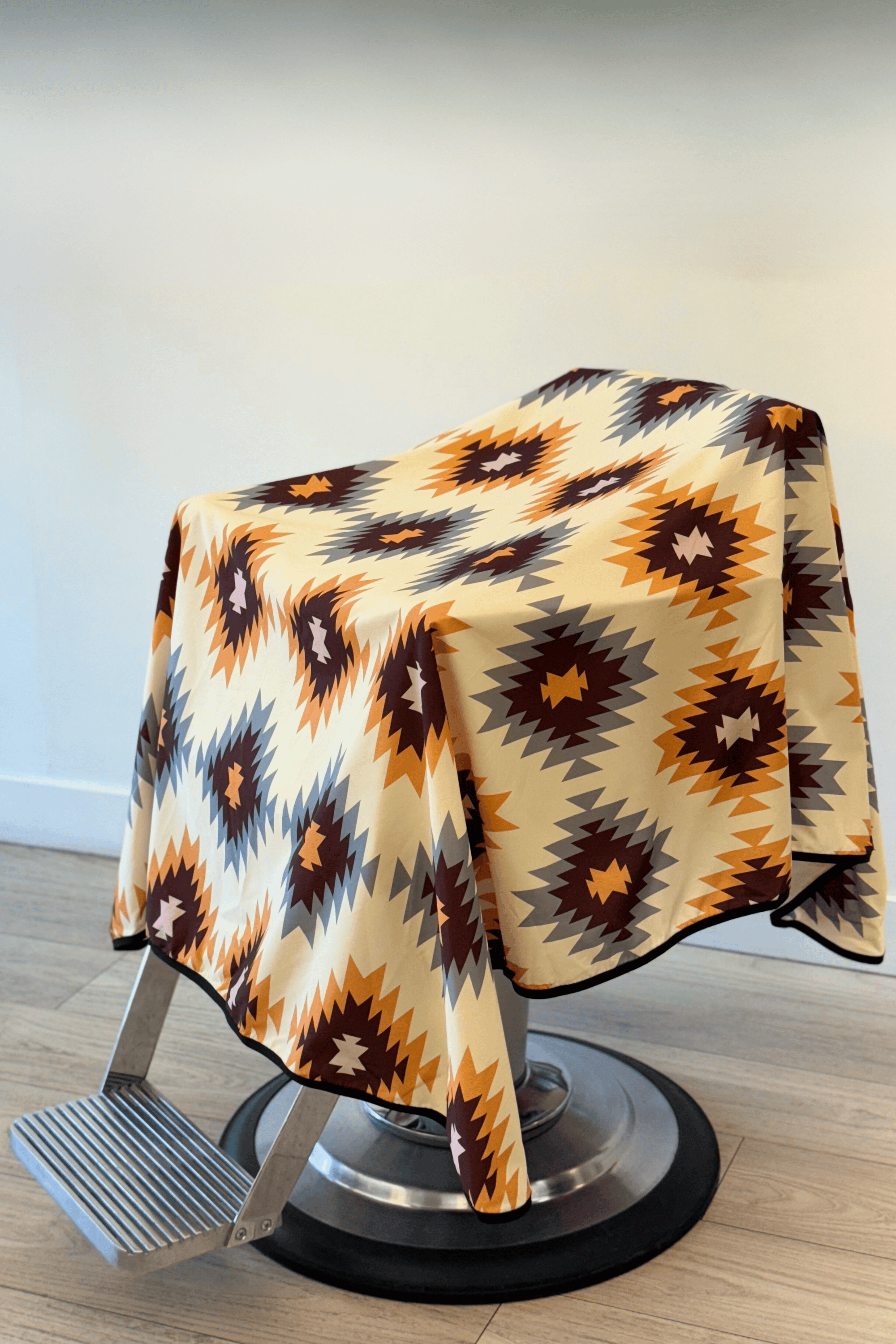 western barber cutting cape draped on barber chair. Geometric pattern in warm colors