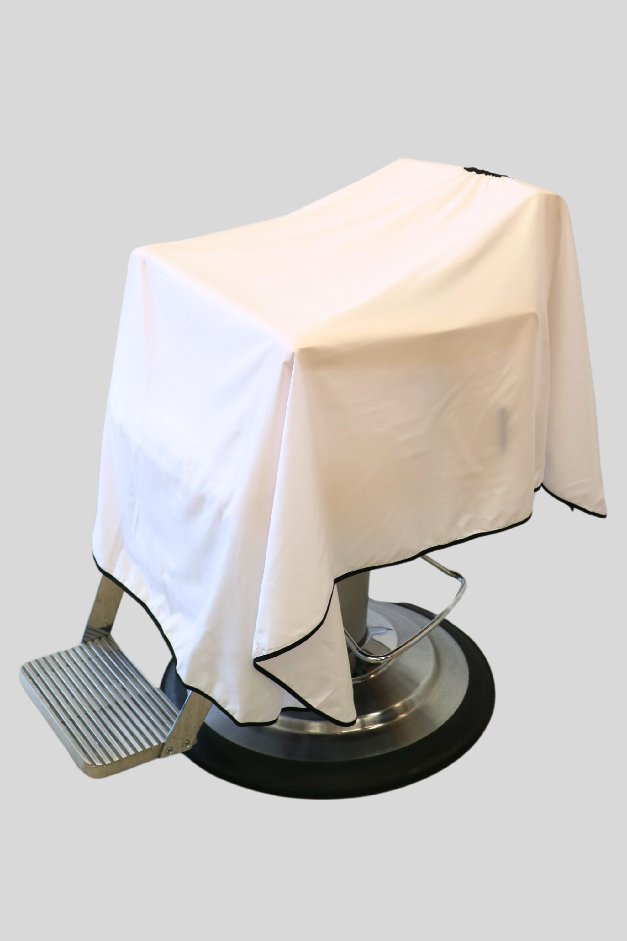 classic white barber cape draped on barber chair