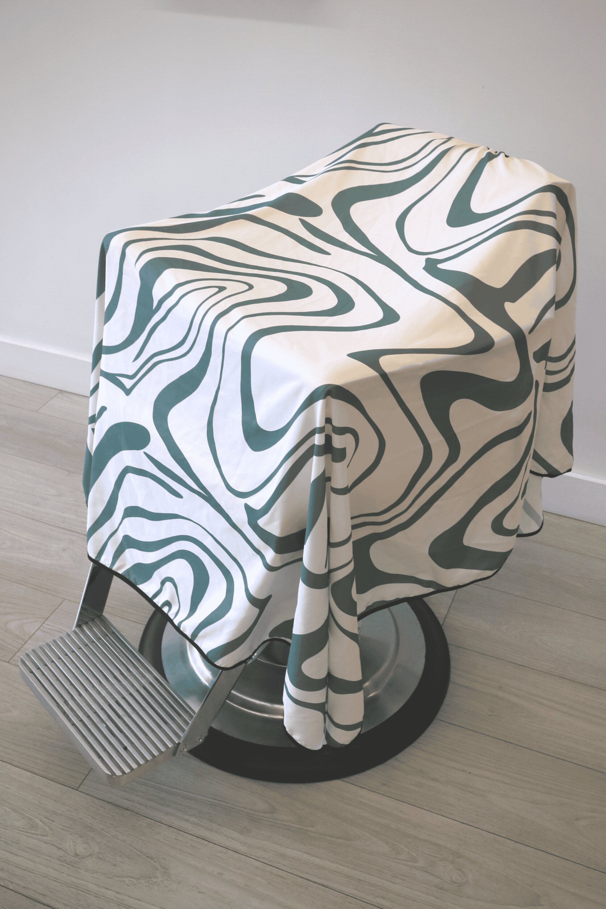 Angled view of the Aurora Cape, a white and green barber cape by High Top Capes.